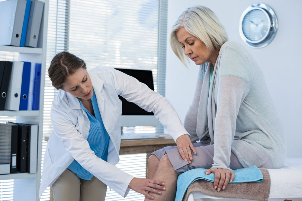 doctor-examines-woman-patient-knee